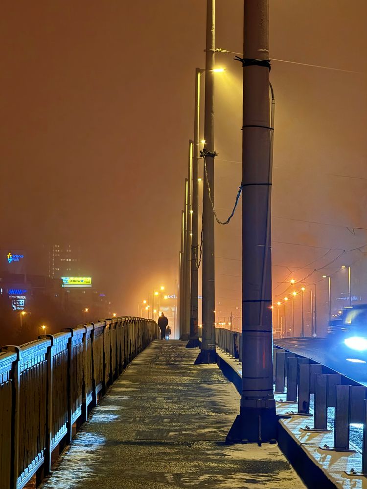 Budapester Brücke bei Nacht im Schneenebel, Straßenlaternen und eine einzelne Person auf dem Gehweg