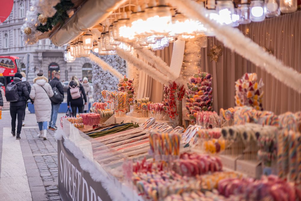 Süßwarenstand auf einem Budapester Markt mit bunten Lutschern und Lichterketten
